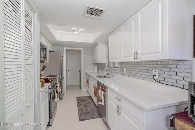 kitchen featuring visible vents, decorative backsplash, stainless steel appliances, white cabinetry, and a sink