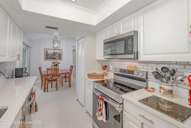 kitchen with white cabinets, visible vents, stainless steel appliances, and backsplash