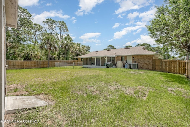 view of yard with a fenced backyard, a sunroom, and central air condition unit