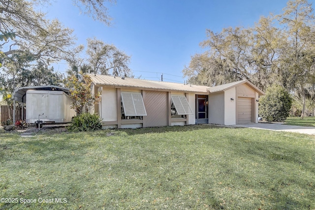 view of front of home featuring metal roof, driveway, a front lawn, and an attached garage