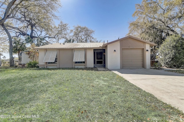 ranch-style home featuring a garage, a front lawn, metal roof, and concrete driveway