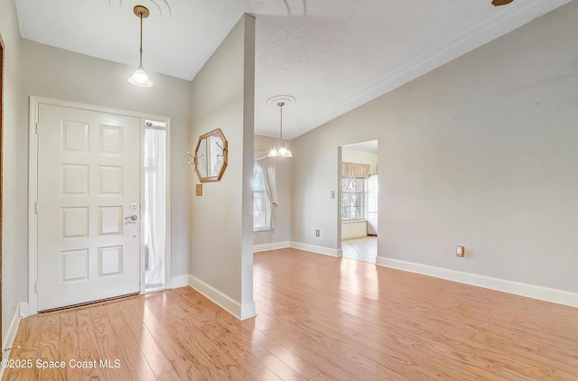 entryway featuring light wood-type flooring, vaulted ceiling, a textured ceiling, and baseboards