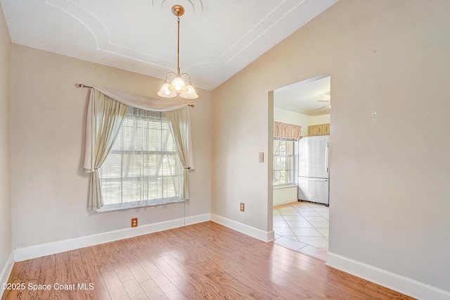 spare room with vaulted ceiling, a notable chandelier, baseboards, and wood finished floors