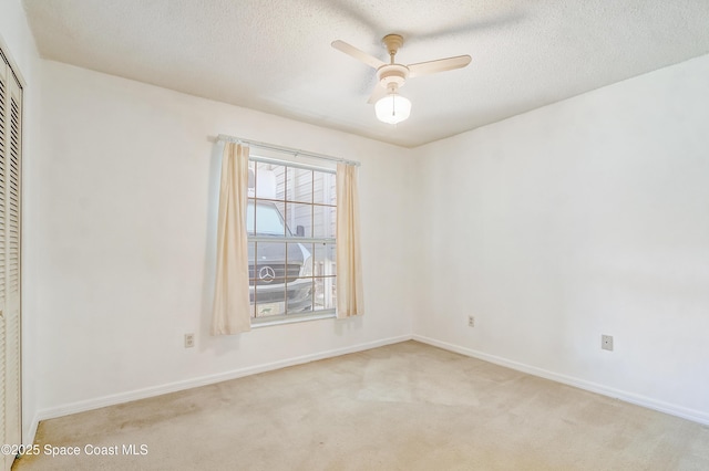 unfurnished room featuring light colored carpet, ceiling fan, a textured ceiling, and baseboards