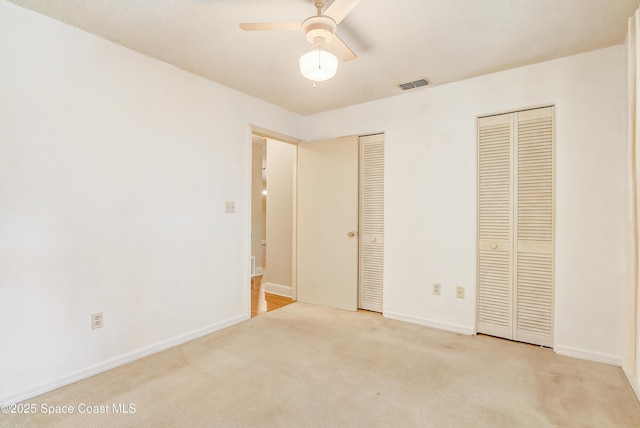 unfurnished bedroom featuring carpet flooring, two closets, visible vents, and baseboards