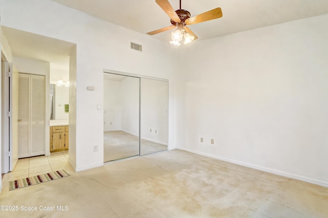 unfurnished bedroom with baseboards, visible vents, light colored carpet, ensuite bathroom, and a closet