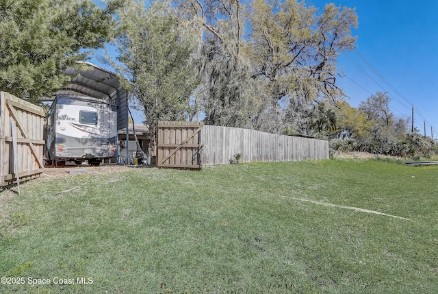 view of yard featuring a carport, a gate, and fence