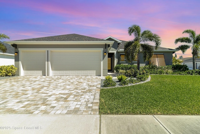 view of front of home featuring a front lawn, roof with shingles, stucco siding, decorative driveway, and a garage