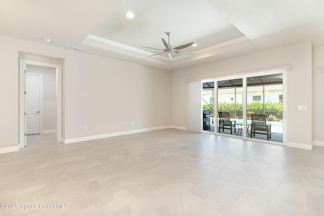 unfurnished room with baseboards, a tray ceiling, recessed lighting, a sunroom, and ceiling fan