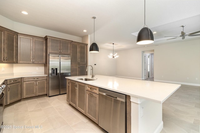 kitchen with open floor plan, an island with sink, light countertops, appliances with stainless steel finishes, and a sink