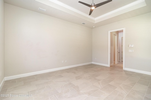 spare room with a ceiling fan, baseboards, visible vents, a tray ceiling, and ornamental molding