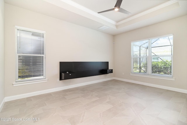 interior space with baseboards, a raised ceiling, a ceiling fan, and crown molding