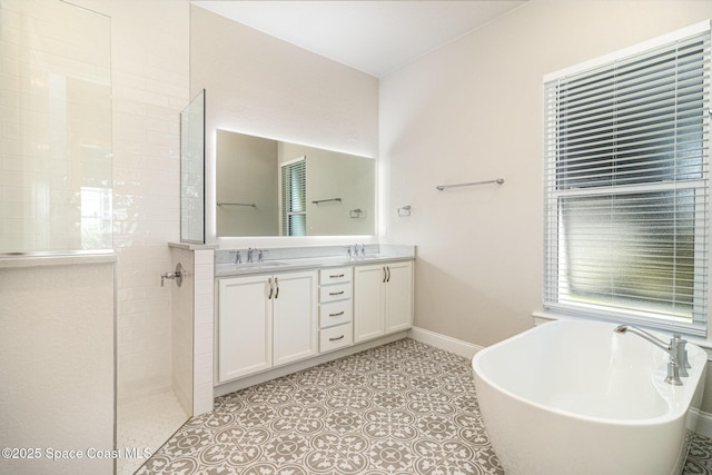 bathroom featuring a walk in shower, a sink, double vanity, baseboards, and a soaking tub