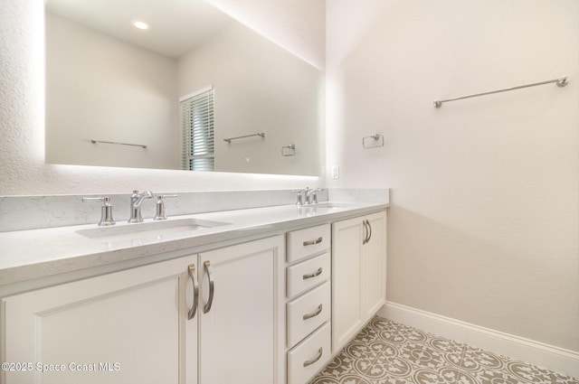 full bath featuring a sink, baseboards, double vanity, and tile patterned flooring