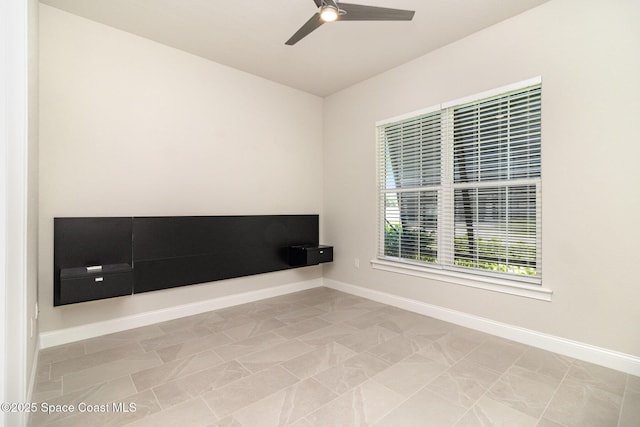 interior space with a ceiling fan and baseboards