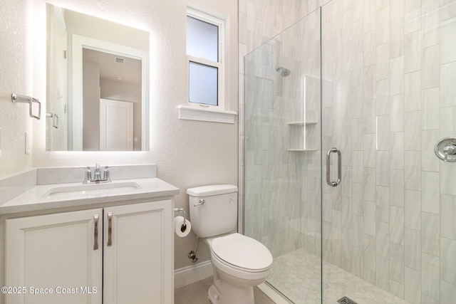 bathroom featuring baseboards, toilet, a stall shower, a textured wall, and vanity