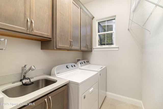 clothes washing area featuring washer and dryer, baseboards, cabinet space, and a sink