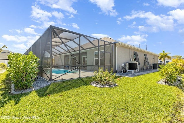 rear view of house with stucco siding, a patio, a lawn, and glass enclosure