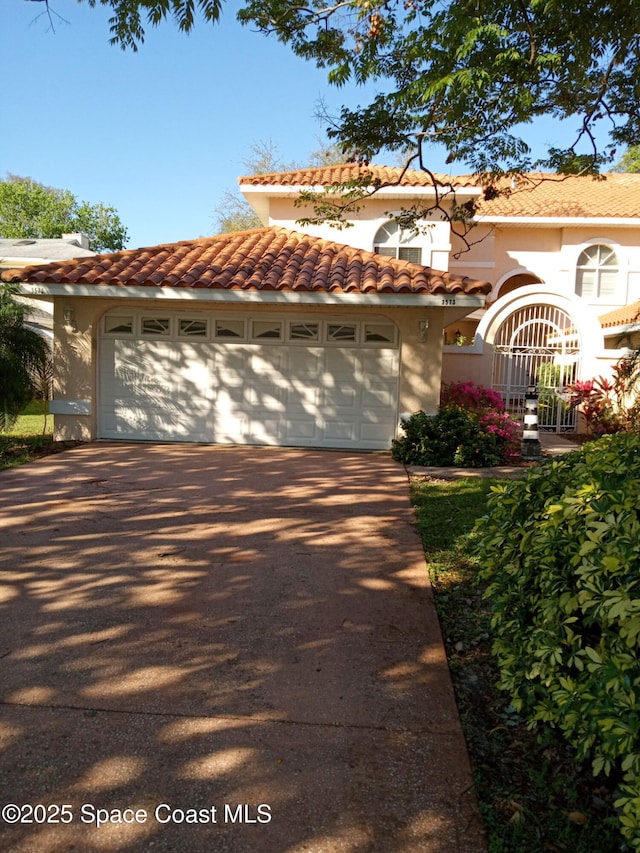 mediterranean / spanish home featuring stucco siding, concrete driveway, an attached garage, and a tile roof