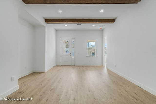 unfurnished living room featuring light wood-style floors, beamed ceiling, and baseboards