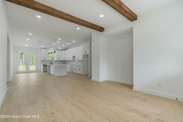 unfurnished living room featuring french doors, recessed lighting, a sink, light wood-type flooring, and baseboards