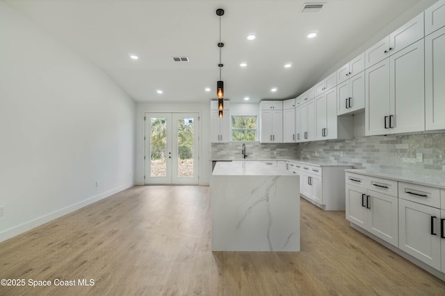 kitchen featuring light wood-type flooring, visible vents, backsplash, and a center island