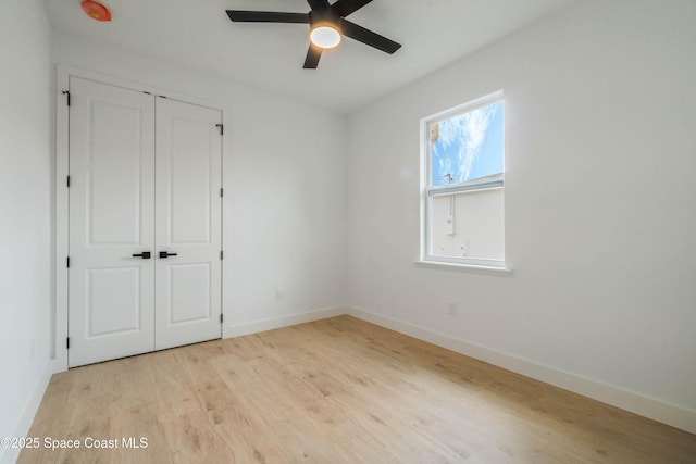 unfurnished bedroom featuring a ceiling fan, a closet, baseboards, and wood finished floors