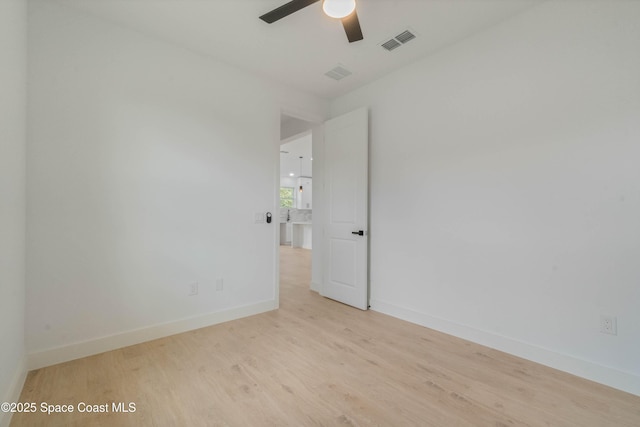 empty room with a ceiling fan, baseboards, visible vents, and wood finished floors