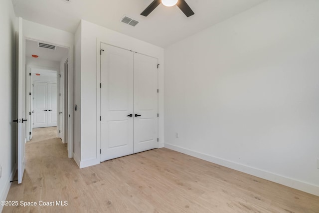 unfurnished bedroom featuring light wood-style floors, baseboards, visible vents, and a closet