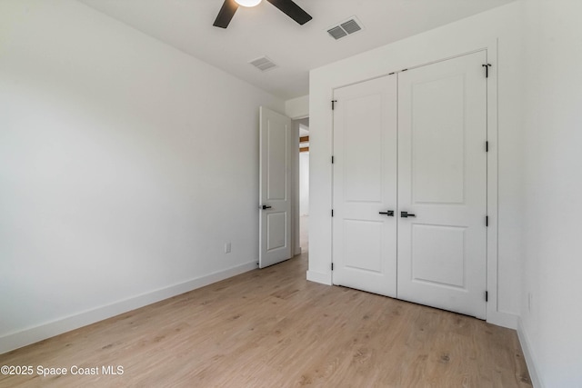 unfurnished bedroom featuring light wood-type flooring, baseboards, visible vents, and a closet