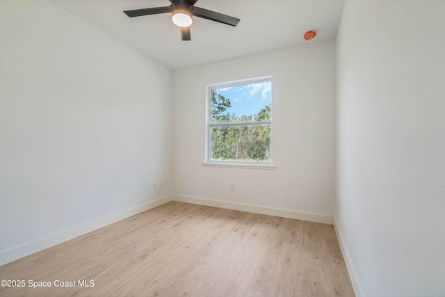 empty room with light wood finished floors, a ceiling fan, and baseboards