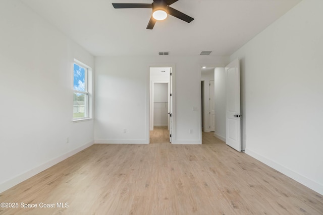 unfurnished bedroom featuring a spacious closet, light wood-type flooring, visible vents, and baseboards