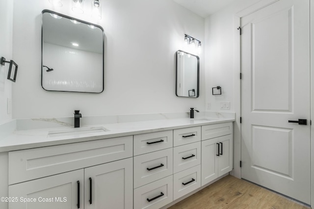 bathroom with double vanity, a sink, and wood finished floors