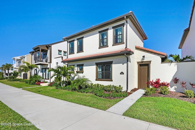 view of front of house with a front yard, a tile roof, a residential view, and stucco siding