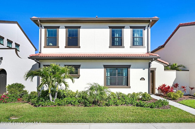 view of front of house with a front lawn, a tile roof, and stucco siding