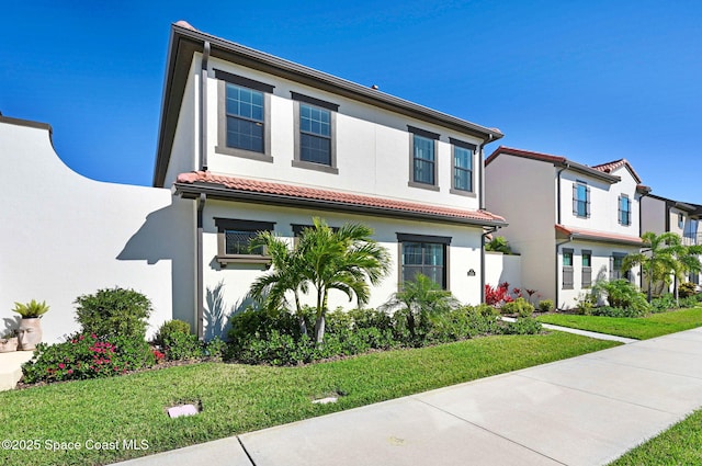 view of front of house featuring a front yard, a tile roof, and stucco siding