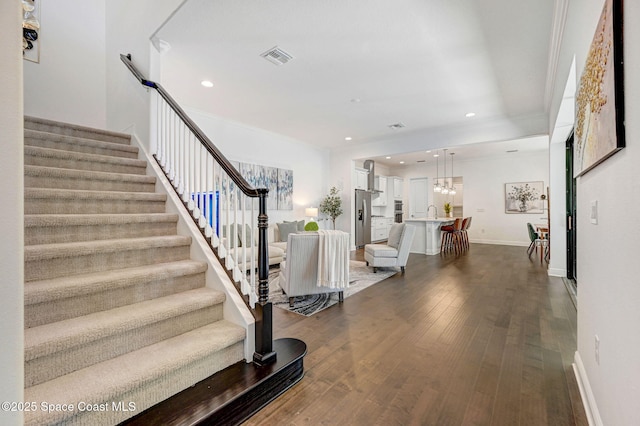 stairs featuring visible vents, hardwood / wood-style floors, recessed lighting, an inviting chandelier, and baseboards