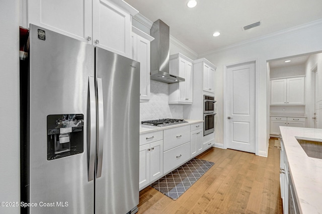 kitchen featuring visible vents, stainless steel appliances, wall chimney exhaust hood, and ornamental molding
