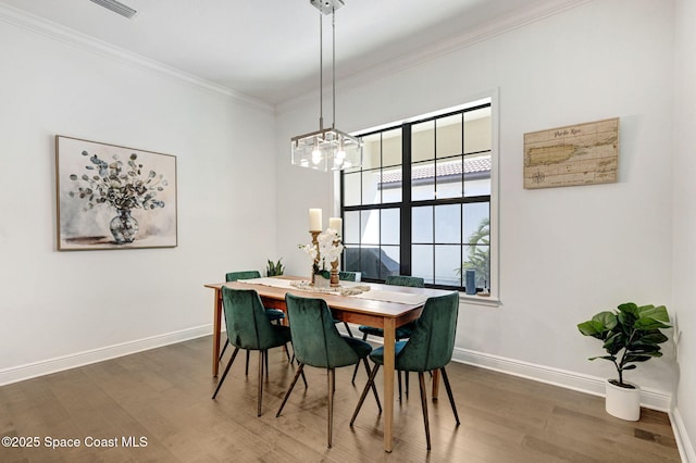 dining room featuring baseboards, wood finished floors, a notable chandelier, and ornamental molding