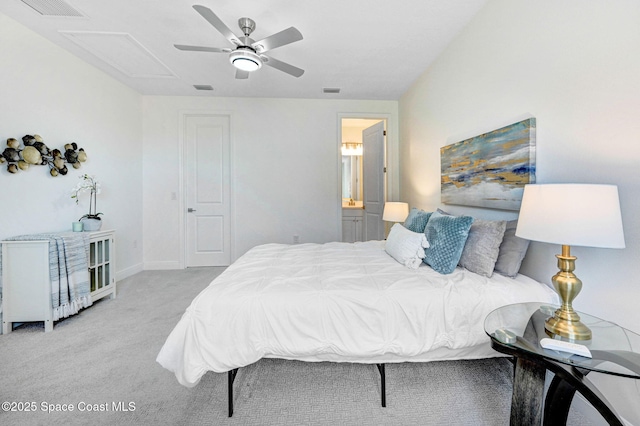 carpeted bedroom with visible vents, baseboards, ceiling fan, attic access, and ensuite bath