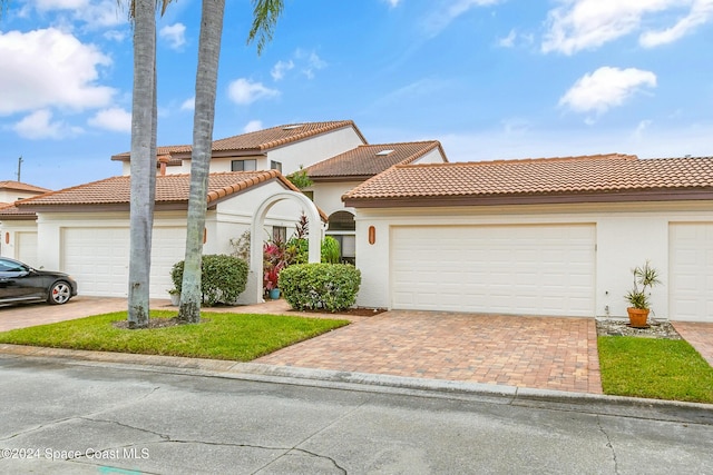 mediterranean / spanish-style home with an attached garage, decorative driveway, and stucco siding