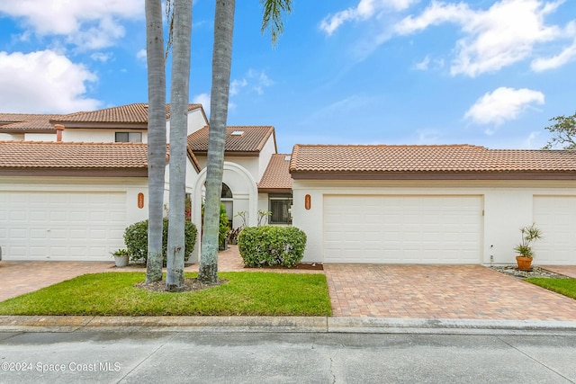 view of front of property featuring decorative driveway, an attached garage, and stucco siding