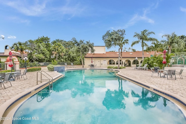 pool with a patio area and fence