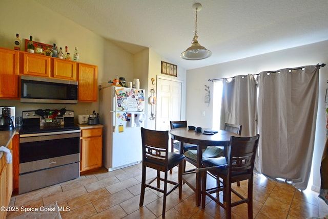 kitchen with appliances with stainless steel finishes, brown cabinets, and decorative light fixtures