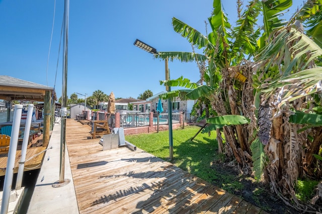 dock area featuring a community pool, fence, and a yard