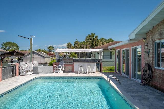 view of swimming pool with fence, outdoor dry bar, grilling area, a fenced in pool, and a patio area