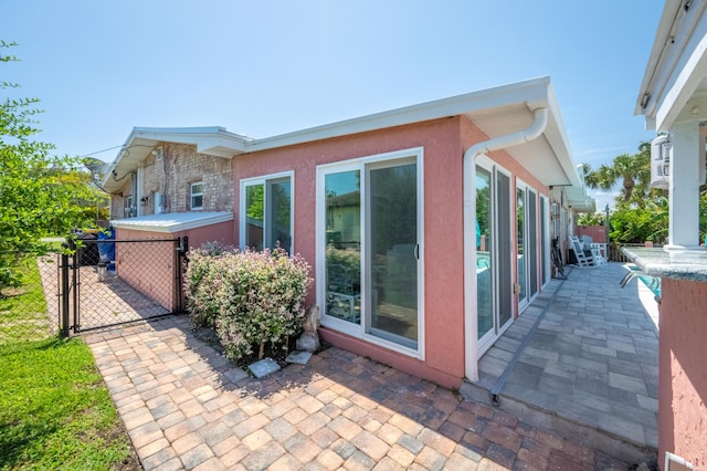 view of side of property featuring a patio area, fence, a gate, and stucco siding