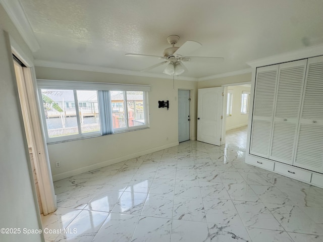 interior space with plenty of natural light, marble finish floor, crown molding, and baseboards