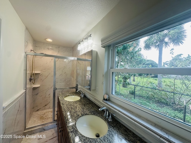 bathroom featuring marble finish floor, a sink, a textured ceiling, and a marble finish shower