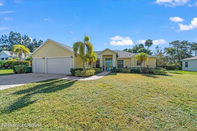 ranch-style home featuring decorative driveway, a front yard, french doors, and an attached garage